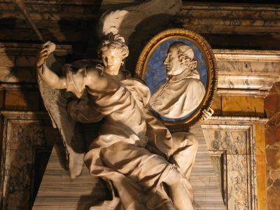 monumento funebre del Card. Fabrizio Paolucci
di Pietro Bracci (1729): La fama regge il ritratto del Cardinale rappresentato entro un ovale di marmo bianco su sfondo di lapislazzuli
